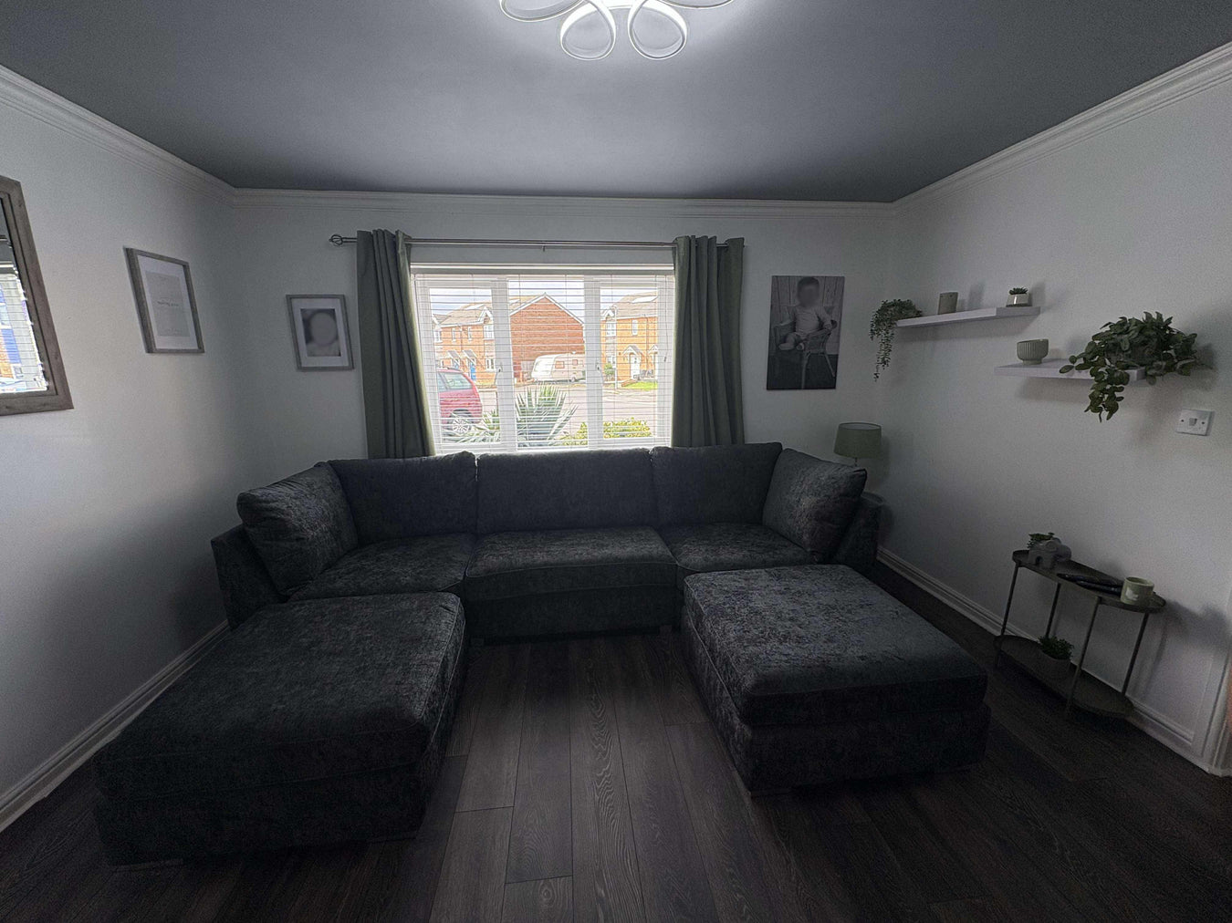 Living room with a dark gray sectional sofa, window, and shelves.